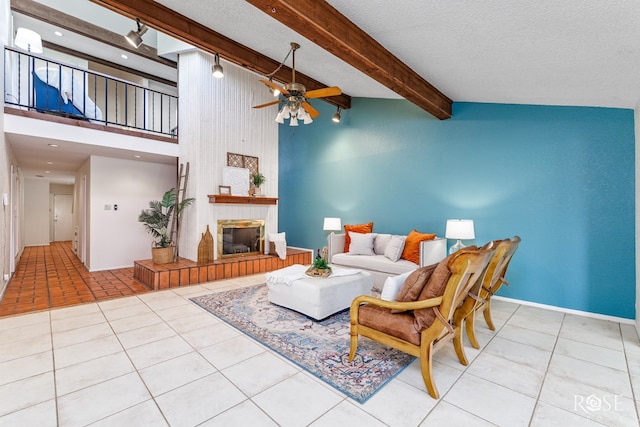 living room featuring light tile patterned floors, ceiling fan, a large fireplace, a textured ceiling, and beamed ceiling