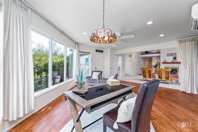 dining room featuring ceiling fan, a wall unit AC, a wealth of natural light, and light wood-type flooring