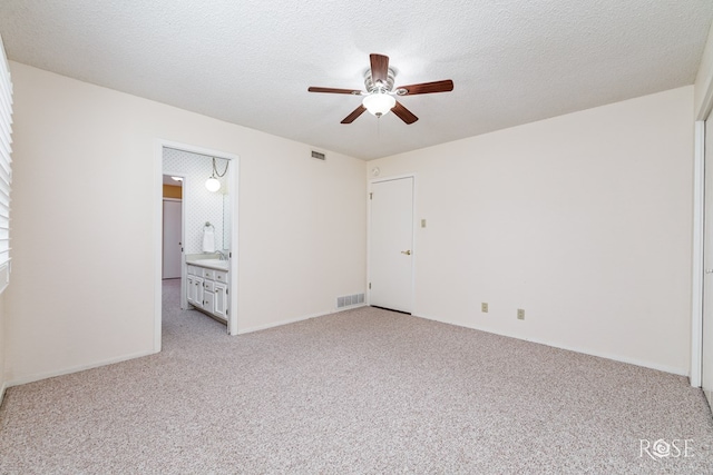 unfurnished bedroom featuring sink, ensuite bath, light colored carpet, a textured ceiling, and ceiling fan