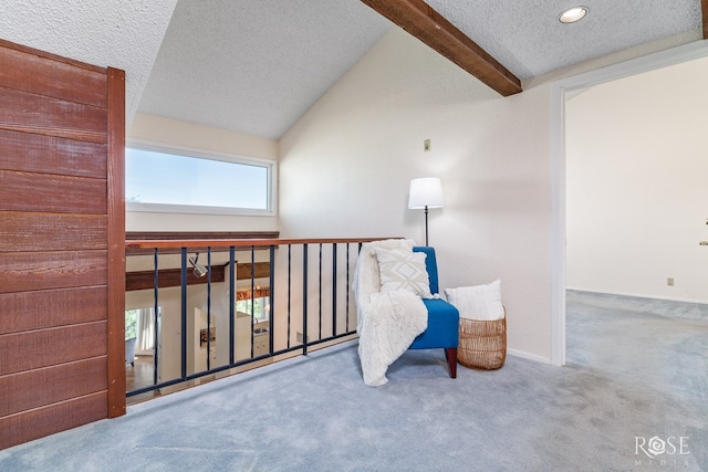 living area featuring lofted ceiling with beams, carpet flooring, and a textured ceiling