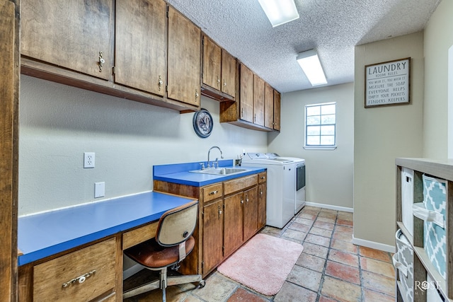 clothes washing area featuring cabinets, sink, washer and dryer, and a textured ceiling