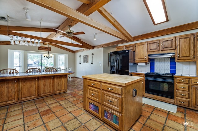 kitchen featuring vaulted ceiling with beams, hanging light fixtures, tasteful backsplash, black appliances, and a kitchen island