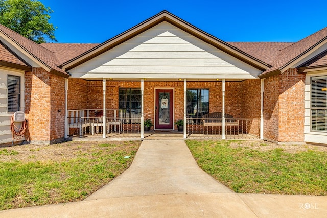 view of exterior entry featuring a porch and a lawn