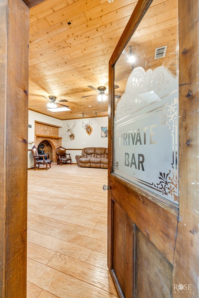 corridor with light hardwood / wood-style flooring and wooden ceiling