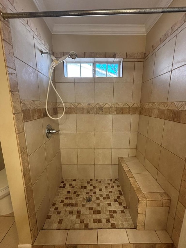 bathroom with a tile shower and crown molding