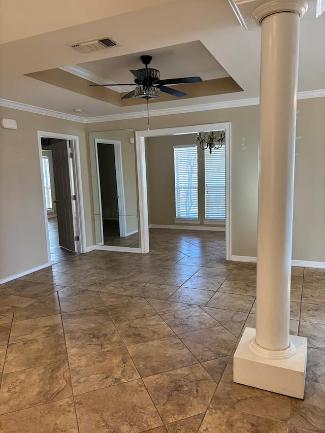 empty room featuring ornamental molding, decorative columns, a raised ceiling, and ceiling fan