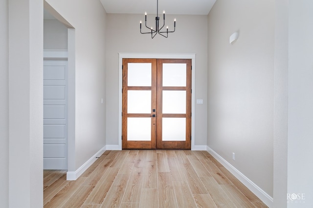 entryway featuring a wealth of natural light, a notable chandelier, light hardwood / wood-style floors, and french doors