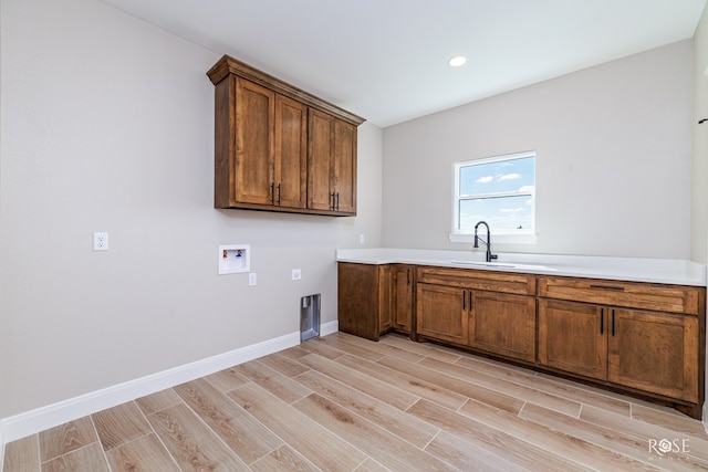 laundry area with cabinets, washer hookup, sink, and light hardwood / wood-style flooring