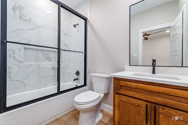 full bathroom with enclosed tub / shower combo, vanity, and toilet