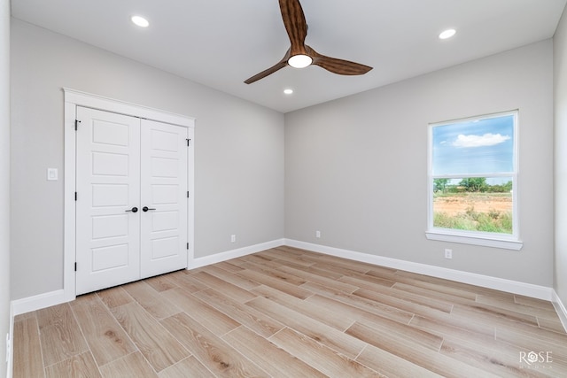 unfurnished bedroom featuring light hardwood / wood-style floors, ceiling fan, and a closet