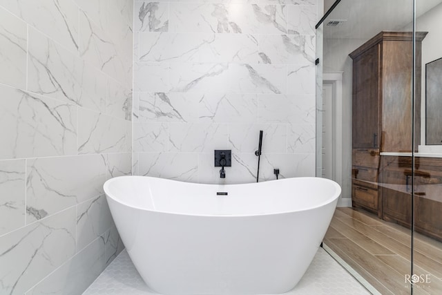 bathroom featuring tile walls, a tub to relax in, and tile patterned flooring