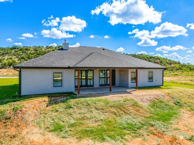 back of house with a patio and a lawn