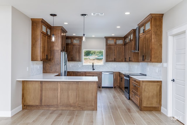 kitchen with sink, decorative light fixtures, appliances with stainless steel finishes, kitchen peninsula, and decorative backsplash