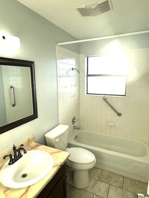 full bathroom featuring vanity, tiled shower / bath combo, tile patterned floors, and toilet