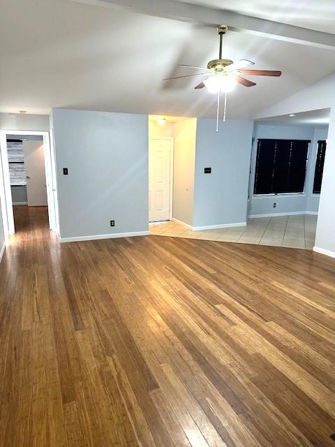 empty room with vaulted ceiling with beams, ceiling fan, and light wood-type flooring