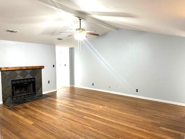 unfurnished living room with lofted ceiling with beams, a tiled fireplace, hardwood / wood-style floors, and ceiling fan