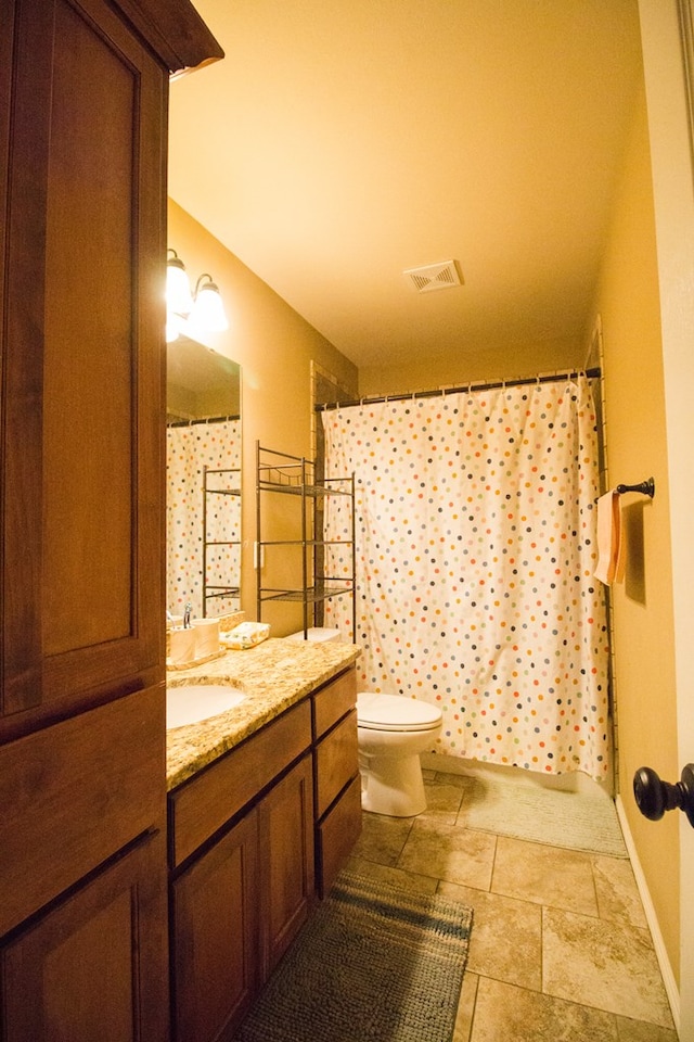 full bath featuring toilet, vanity, visible vents, and baseboards