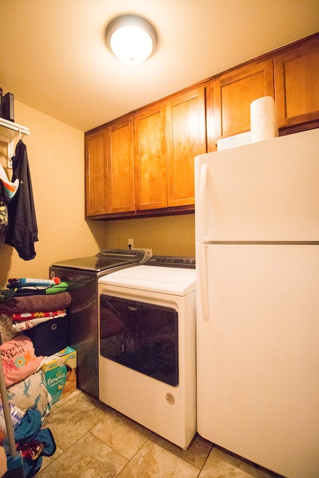 clothes washing area featuring light tile patterned flooring, independent washer and dryer, and cabinet space