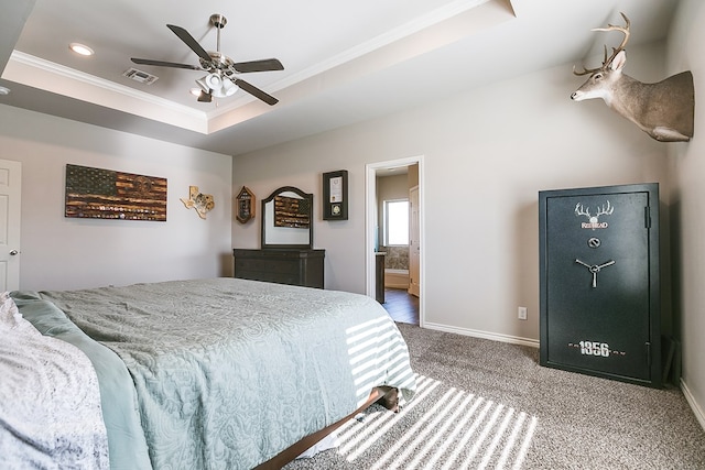 carpeted bedroom with crown molding, ensuite bath, ceiling fan, and a tray ceiling