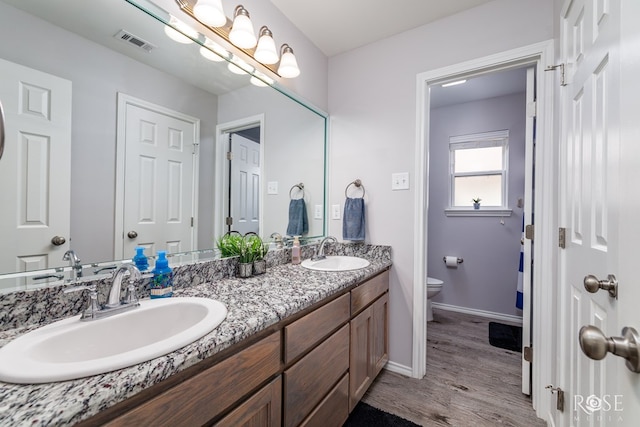 5033 Scarlet Oak Ln, San Angelo, TX 76904 - bathroom featuring toilet, double vanity, wood finished floors, and baseboards