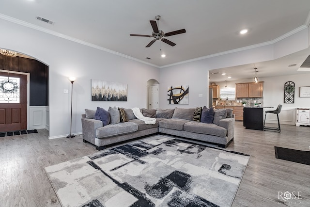 5033 Scarlet Oak Ln, San Angelo, TX 76904 - living room with arched walkways, light wood-style floors, ceiling fan, ornamental molding, and plenty of natural light