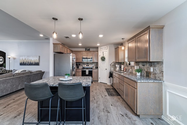5033 Scarlet Oak Ln, San Angelo, TX 76904 - kitchen with stainless steel appliances, light wood finished floors, backsplash, light stone countertops, and recessed lighting