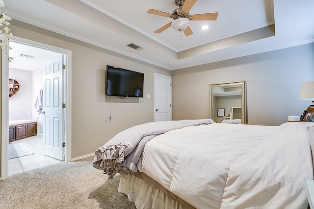 carpeted bedroom featuring a raised ceiling, ensuite bathroom, crown molding, and ceiling fan