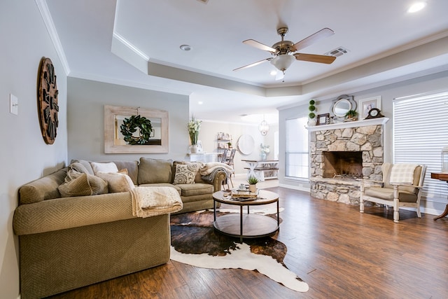 living room with crown molding, a tray ceiling, a fireplace, and dark hardwood / wood-style floors