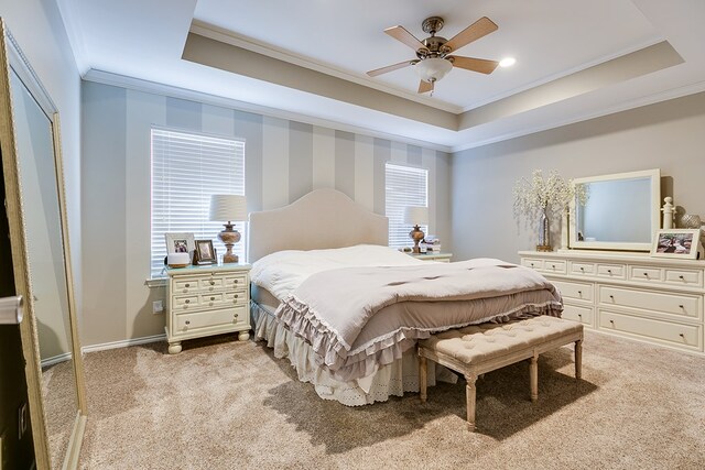 bedroom with ceiling fan, a raised ceiling, and light colored carpet