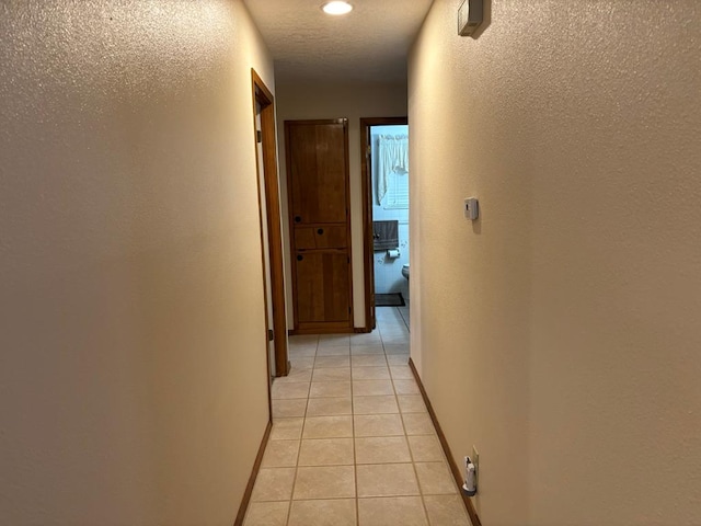 corridor featuring a textured ceiling and light tile patterned floors