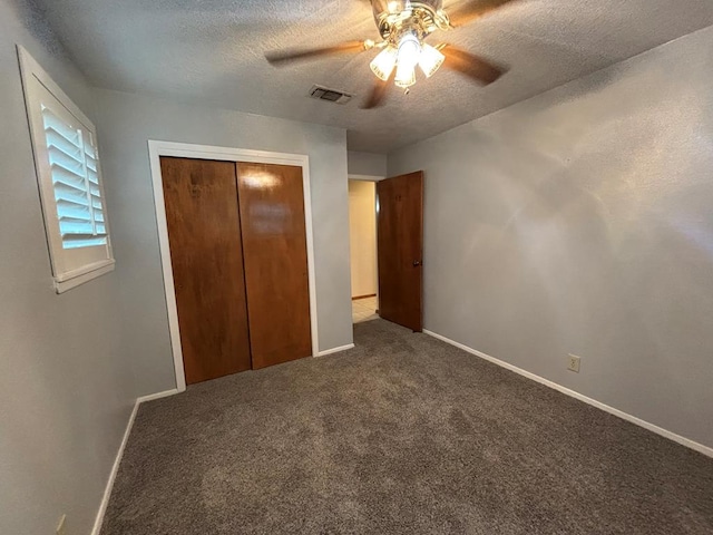 unfurnished bedroom with ceiling fan, a closet, carpet floors, and a textured ceiling