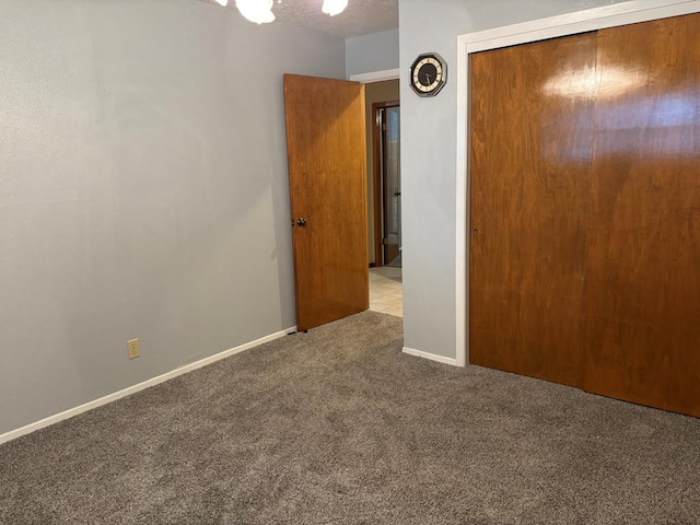 unfurnished bedroom featuring light colored carpet, a textured ceiling, and a closet