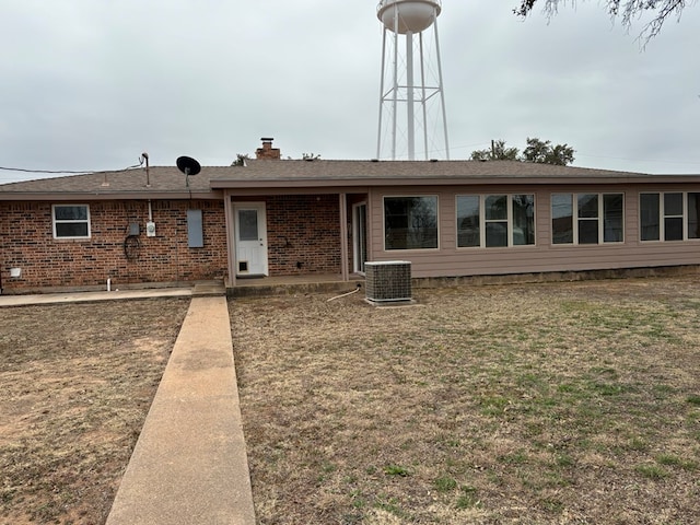 rear view of property featuring a yard and central air condition unit