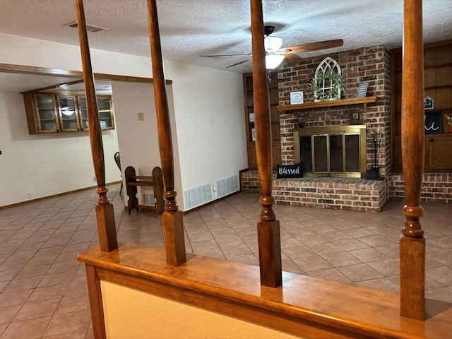 tiled living room with ceiling fan, a textured ceiling, and a fireplace