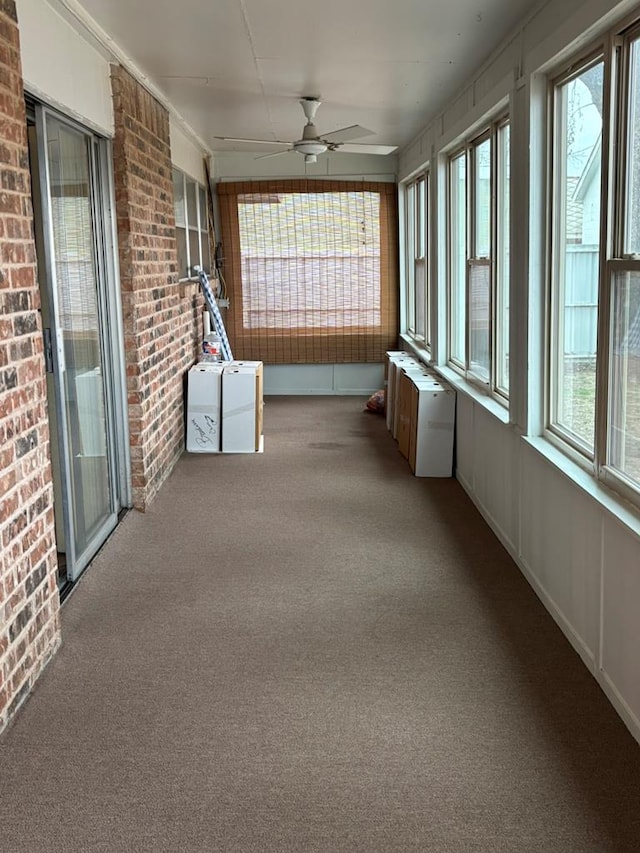 unfurnished sunroom with ceiling fan and radiator heating unit