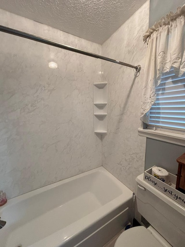 bathroom with tiled shower / bath combo, toilet, and a textured ceiling