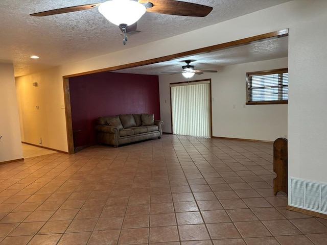 unfurnished living room with tile patterned floors, a textured ceiling, and ceiling fan