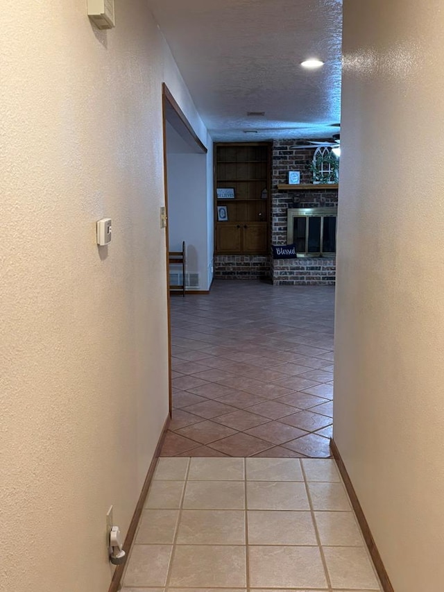 hall with light tile patterned floors and a textured ceiling