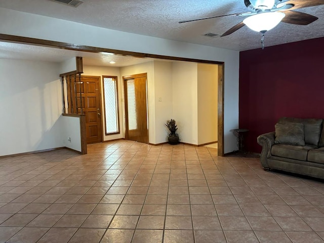 unfurnished living room with ceiling fan, a textured ceiling, and light tile patterned flooring