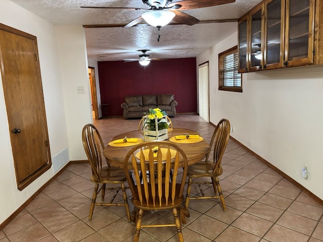 tiled dining space featuring ceiling fan and a textured ceiling