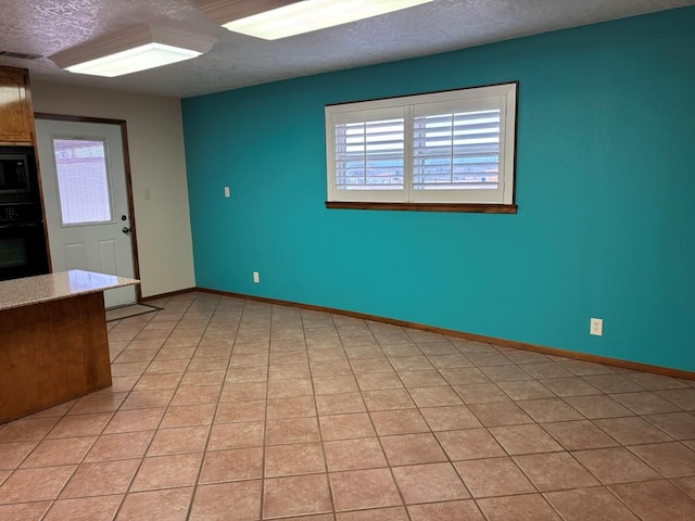 interior space featuring light tile patterned flooring and a textured ceiling