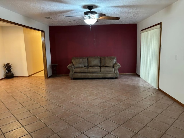 unfurnished living room featuring ceiling fan, light tile patterned floors, and a textured ceiling