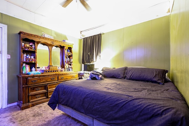 carpeted bedroom featuring wooden walls and ceiling fan