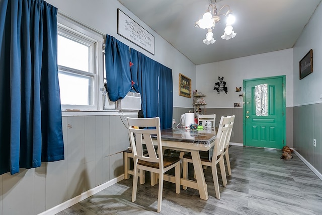 dining space with hardwood / wood-style flooring, cooling unit, and a notable chandelier