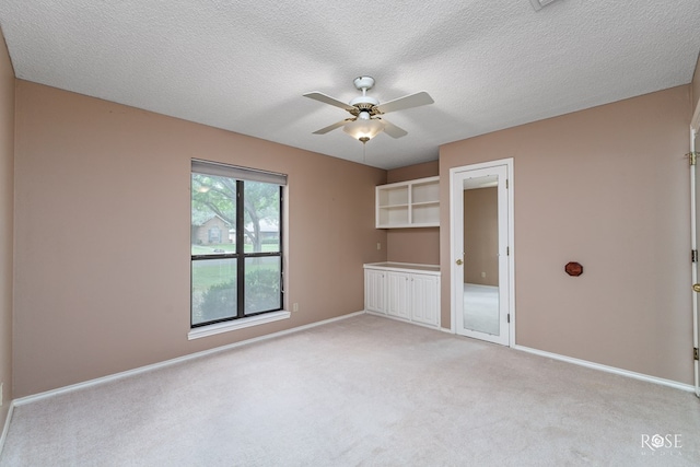 carpeted empty room with ceiling fan and a textured ceiling