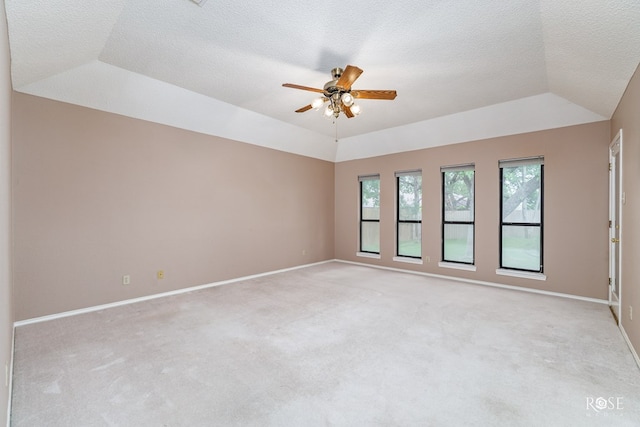 spare room featuring lofted ceiling, ceiling fan, a textured ceiling, light carpet, and a raised ceiling