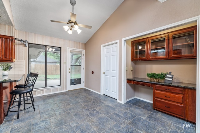 interior space featuring lofted ceiling, built in desk, and ceiling fan