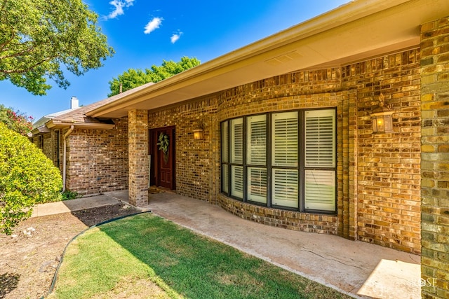 view of exterior entry with a patio area