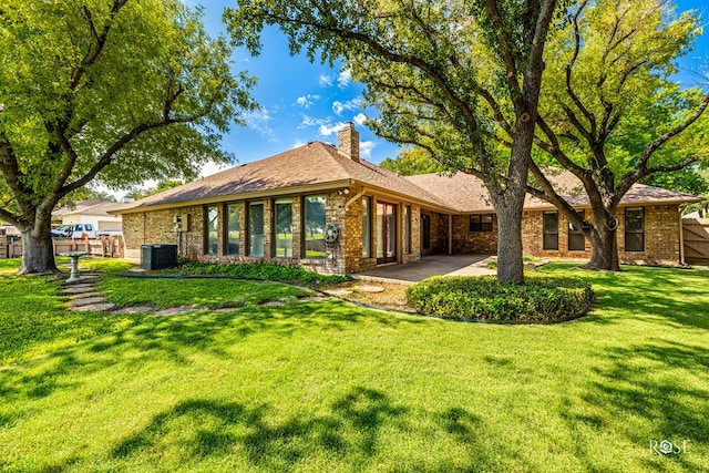 rear view of property featuring a yard, a patio area, and central air condition unit