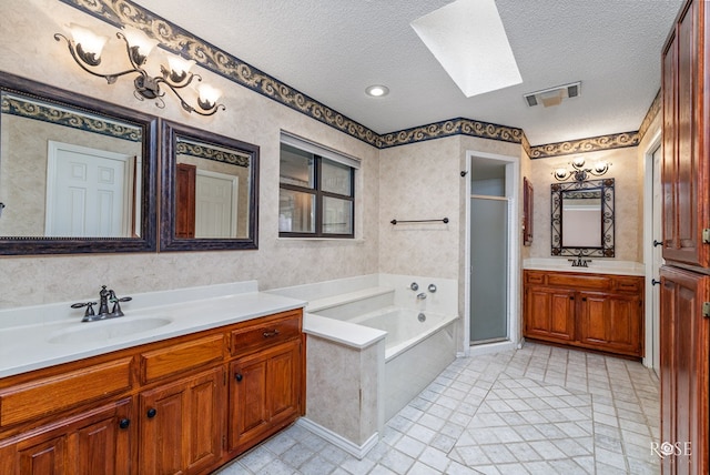 bathroom featuring shower with separate bathtub, vanity, a textured ceiling, and a skylight